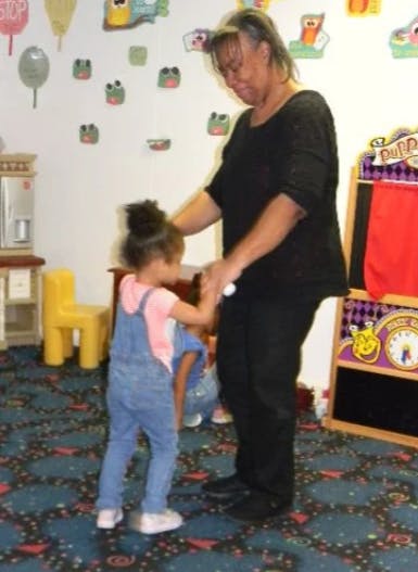 Adult and child holding hands in a classroom