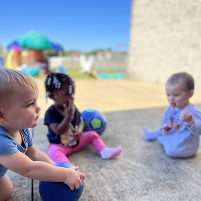 Three children playing with balls outdoors