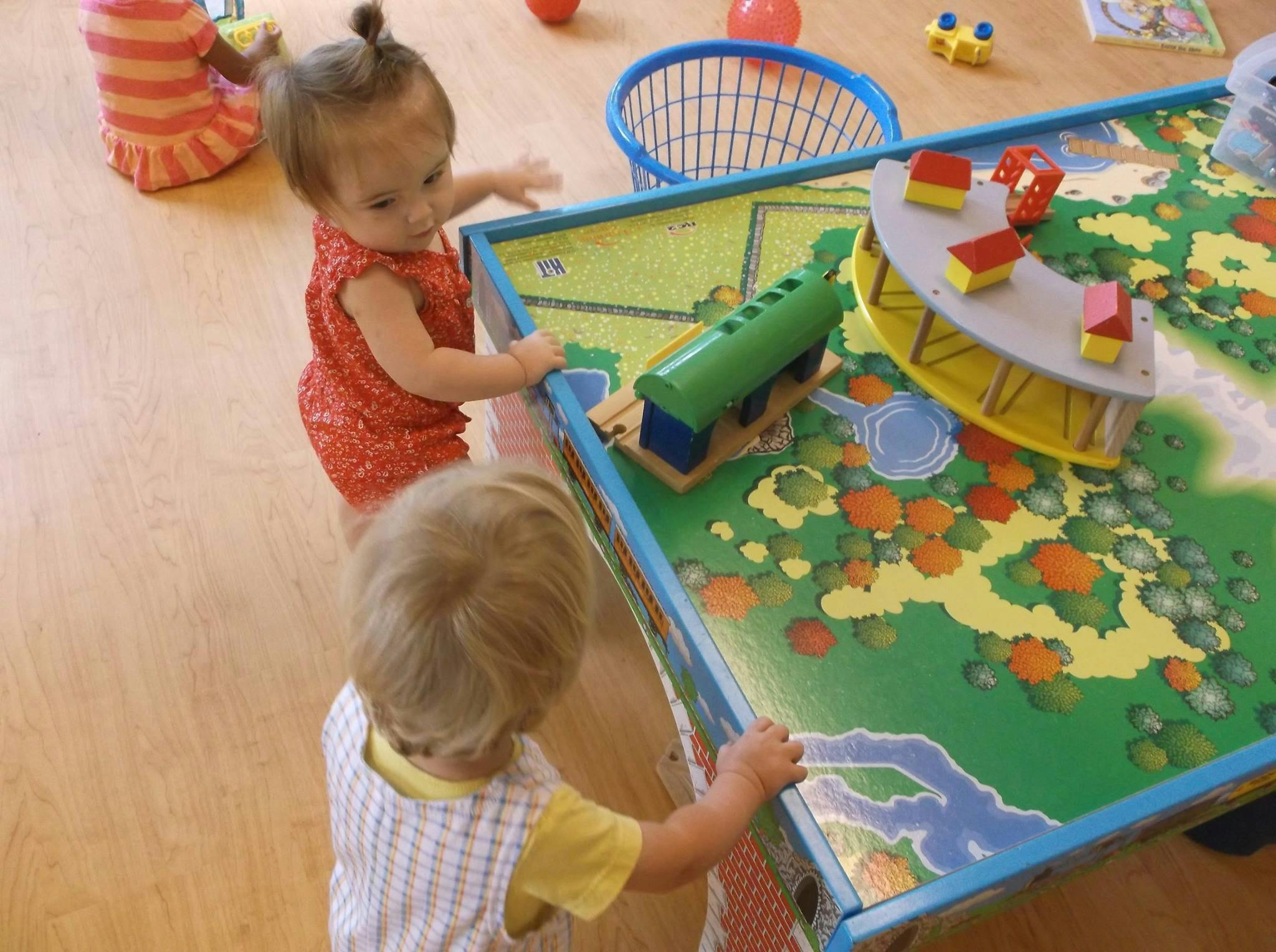 Two children playing with toys on a play table