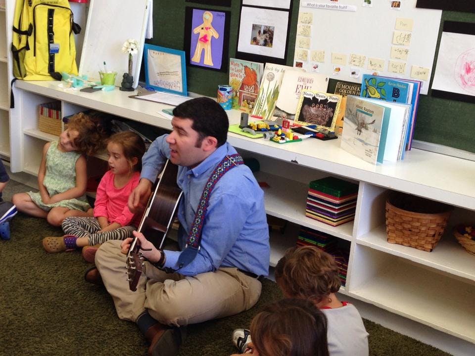 Person playing guitar for children in a classroom