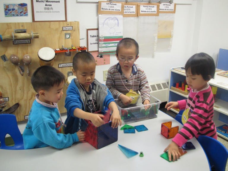 Four children playing with colorful magnetic shapes at a table