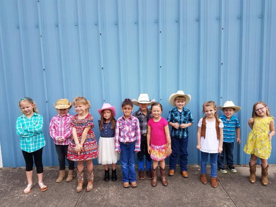 Group of children in cowboy hats and boots standing in a line