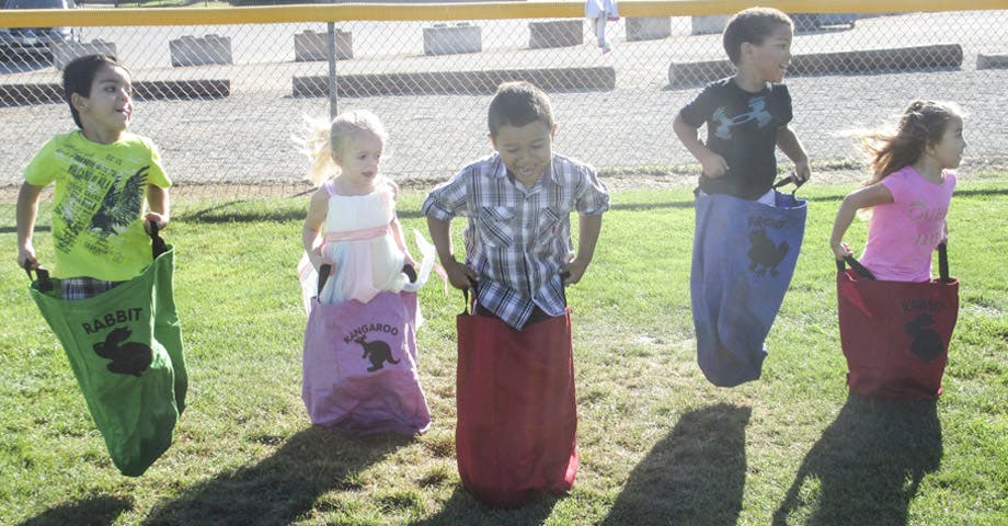 Five children in a sack race on grass