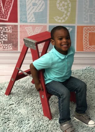 Child sitting on a red step stool