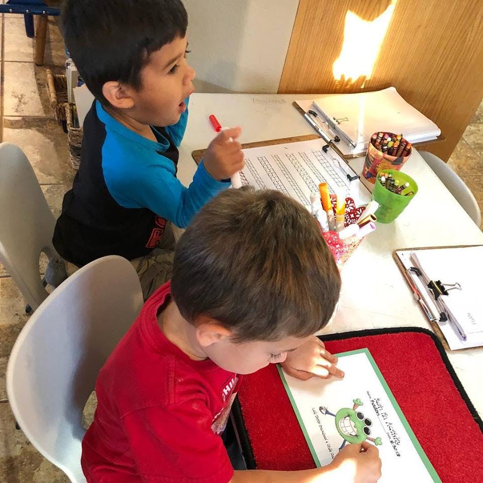 Two children drawing and writing at a table