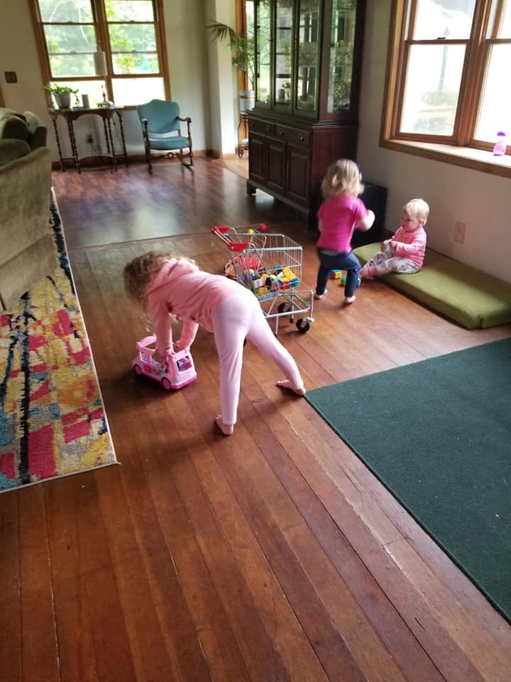 Three children playing with toys on a wooden floor