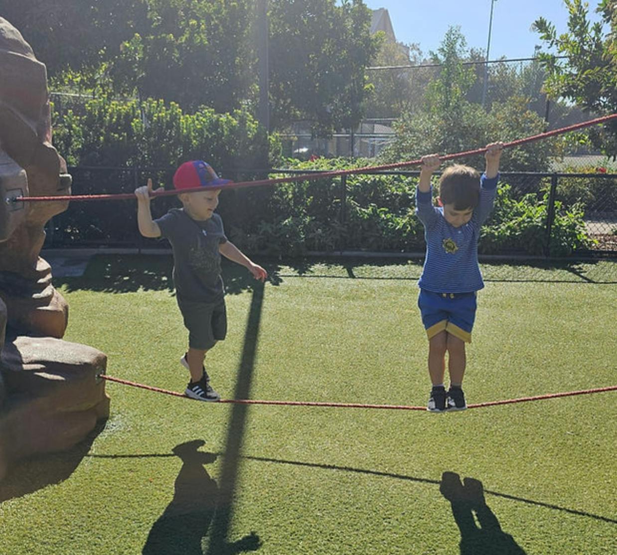 Two children on a playground walking on a rope bridge