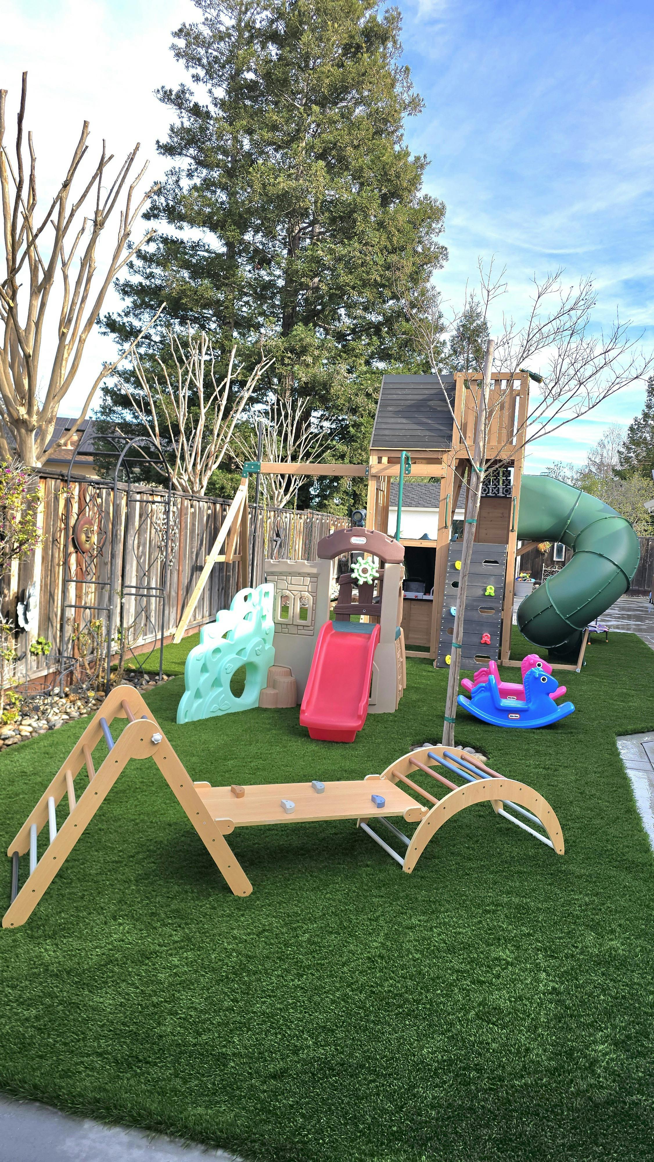 backyard playground with a wooden play structure, slides, and climbing features