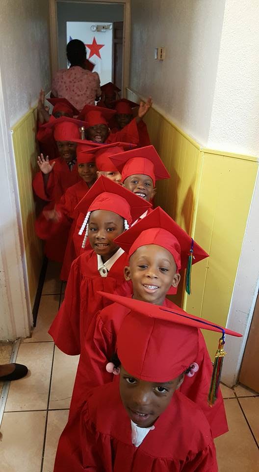 Line of children in red graduation caps and gowns
