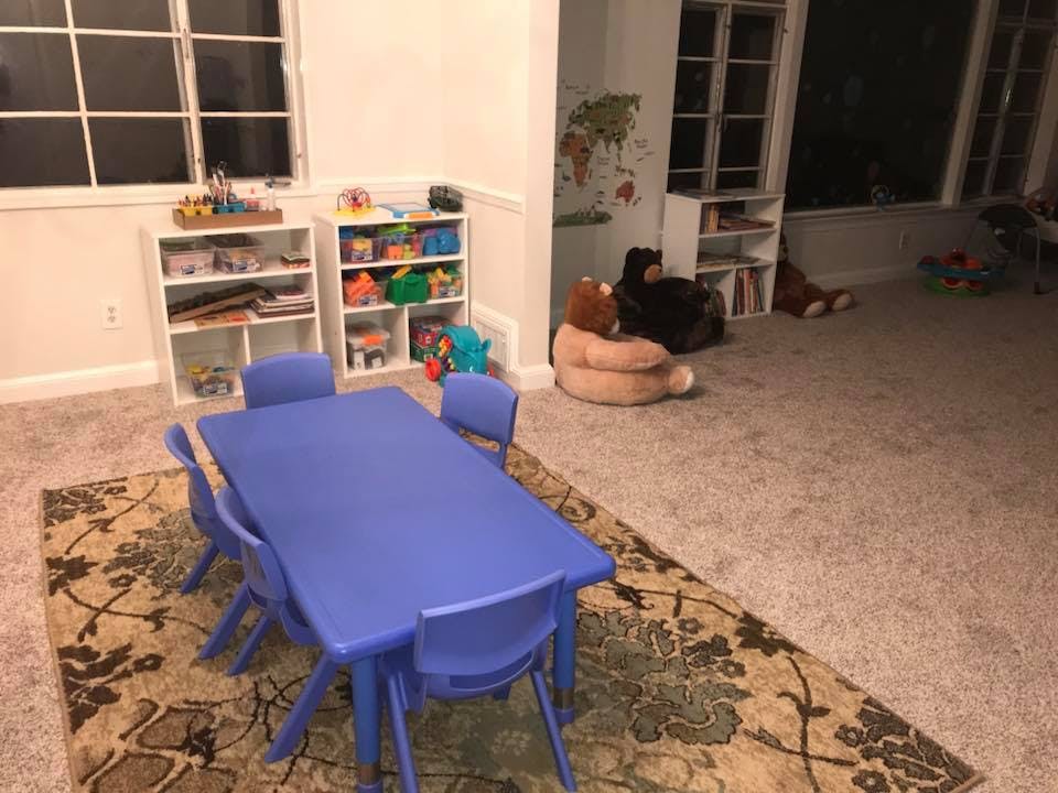 Blue table and chairs in a playroom with shelves of toys