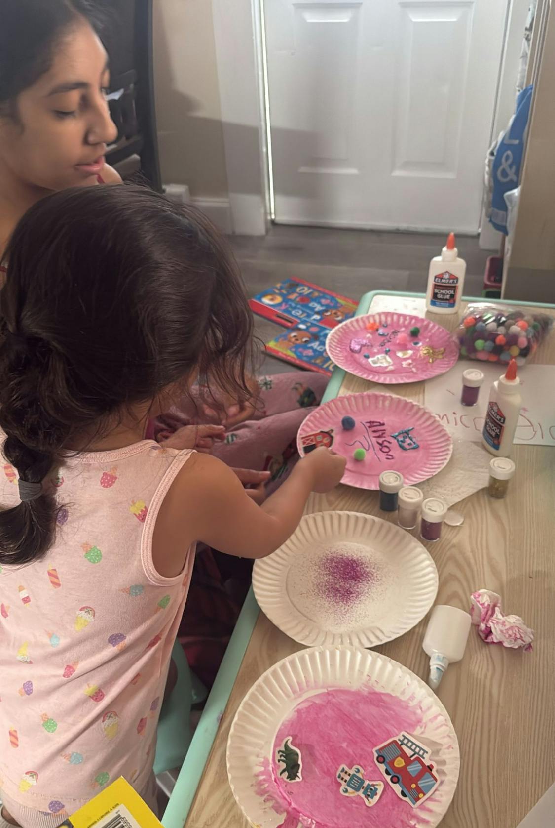 Two children crafting with paper plates, glue, and glitter
