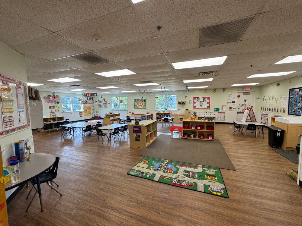 Empty classroom with small tables and chairs, toys, and decorations