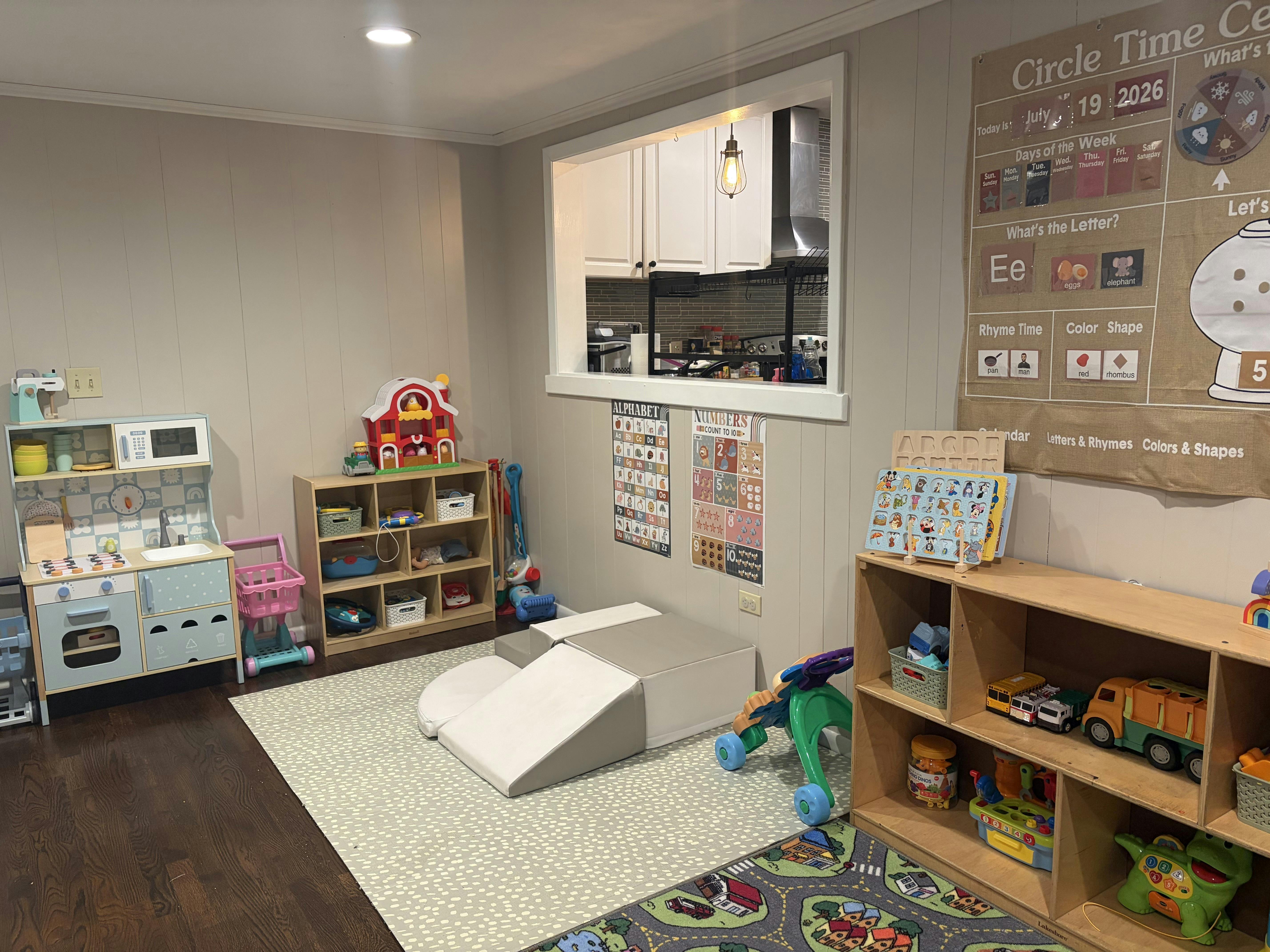 Playroom with shelves, a toy kitchen, and educational posters on the wall