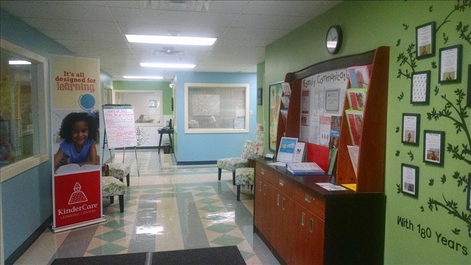 Hallway with a Kindercare banner, informational displays, and a light green wall