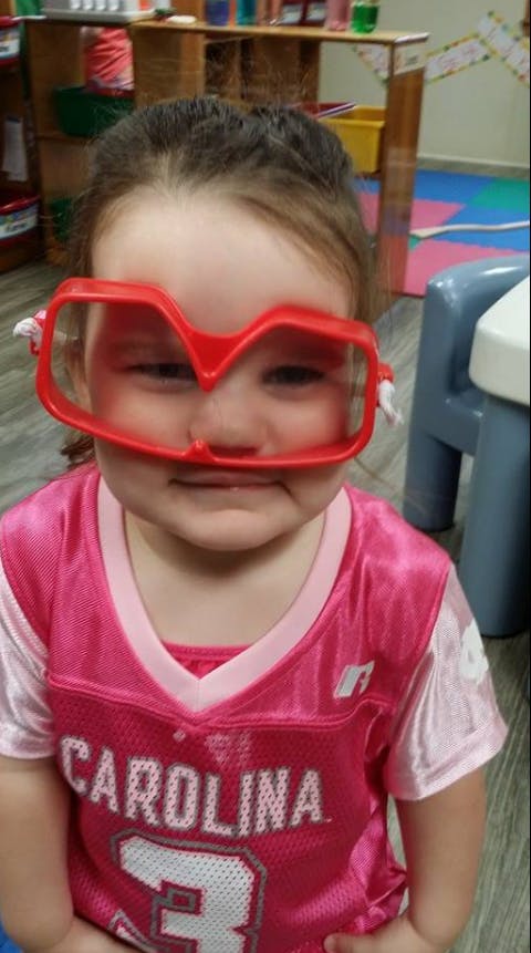 Child wearing oversized red glasses