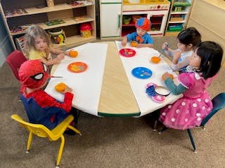 Five children sitting at a table with plates and cups