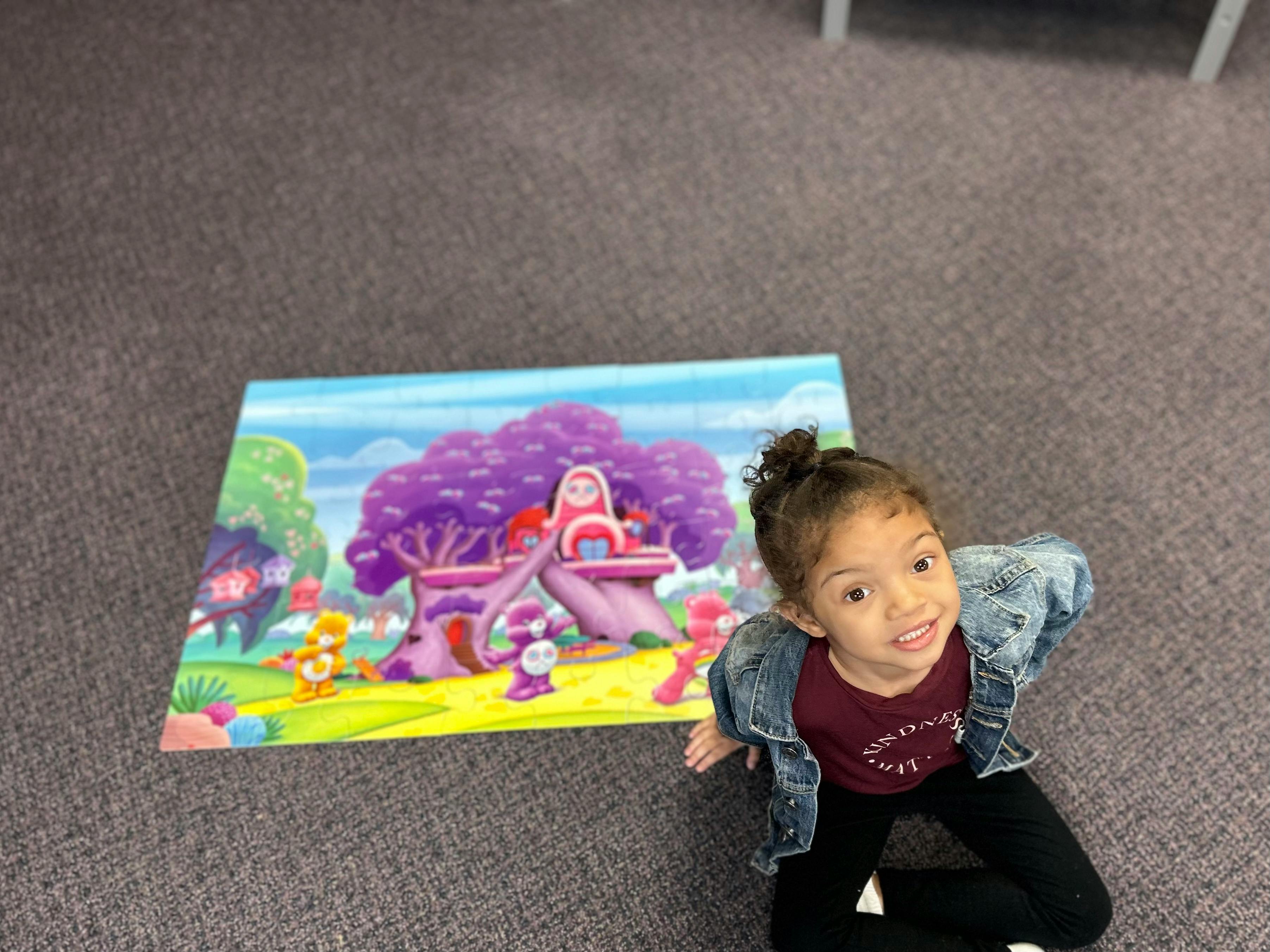 Child sitting on floor next to a colorful cartoon drawing