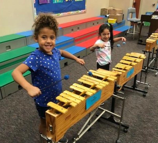 Two children playing xylophones in a classroom