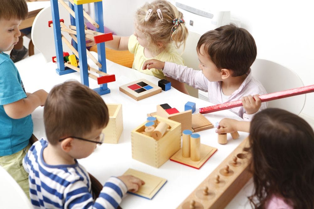 Children playing with wooden toys at a table