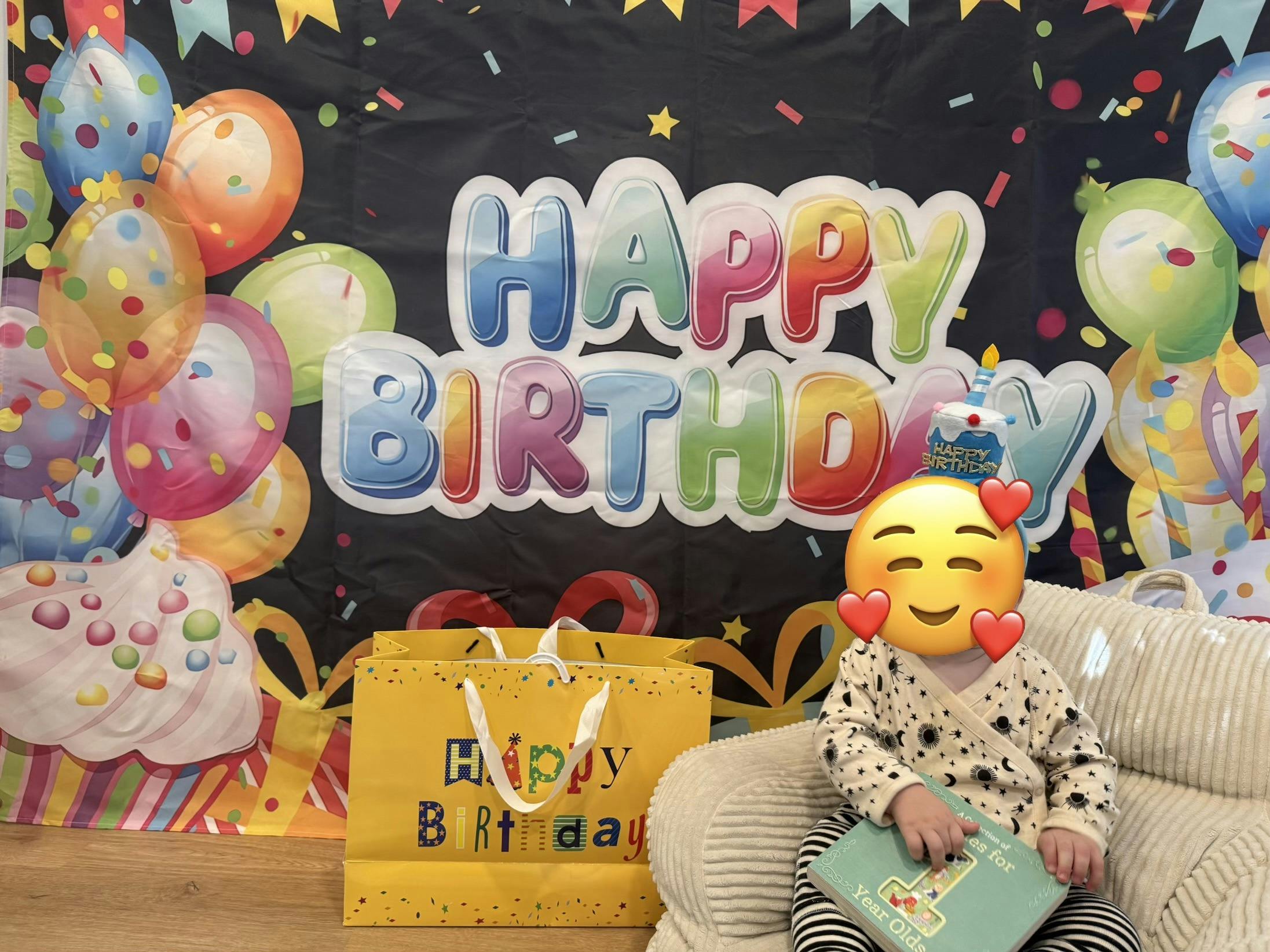 Child sitting in a chair holding a book, with a Happy Birthday banner and gift