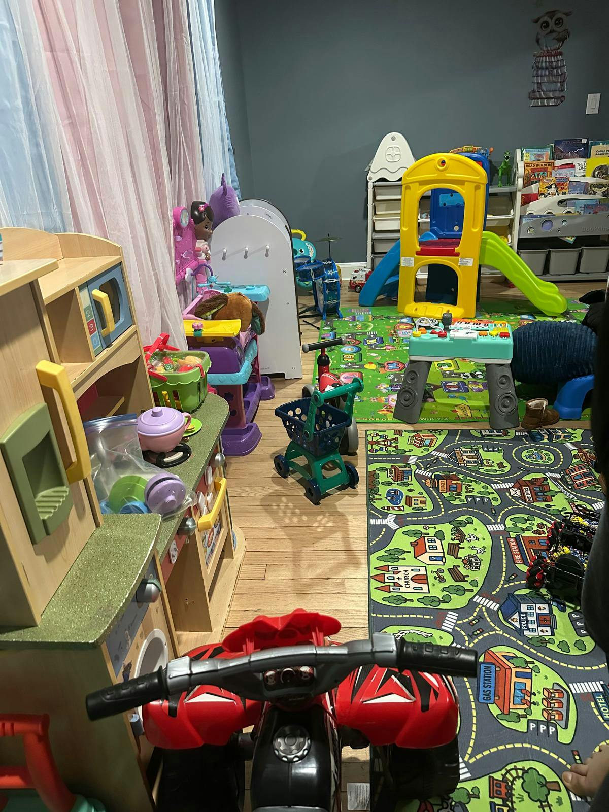 Child's playroom filled with various toys including a kitchen set, slide, and rug