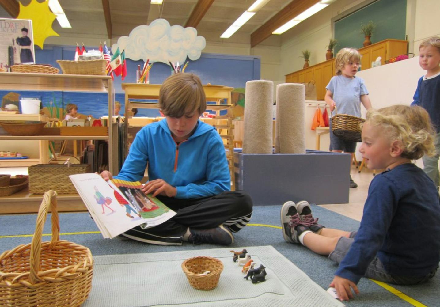 Teen reading a book on the floor with a child sitting nearby