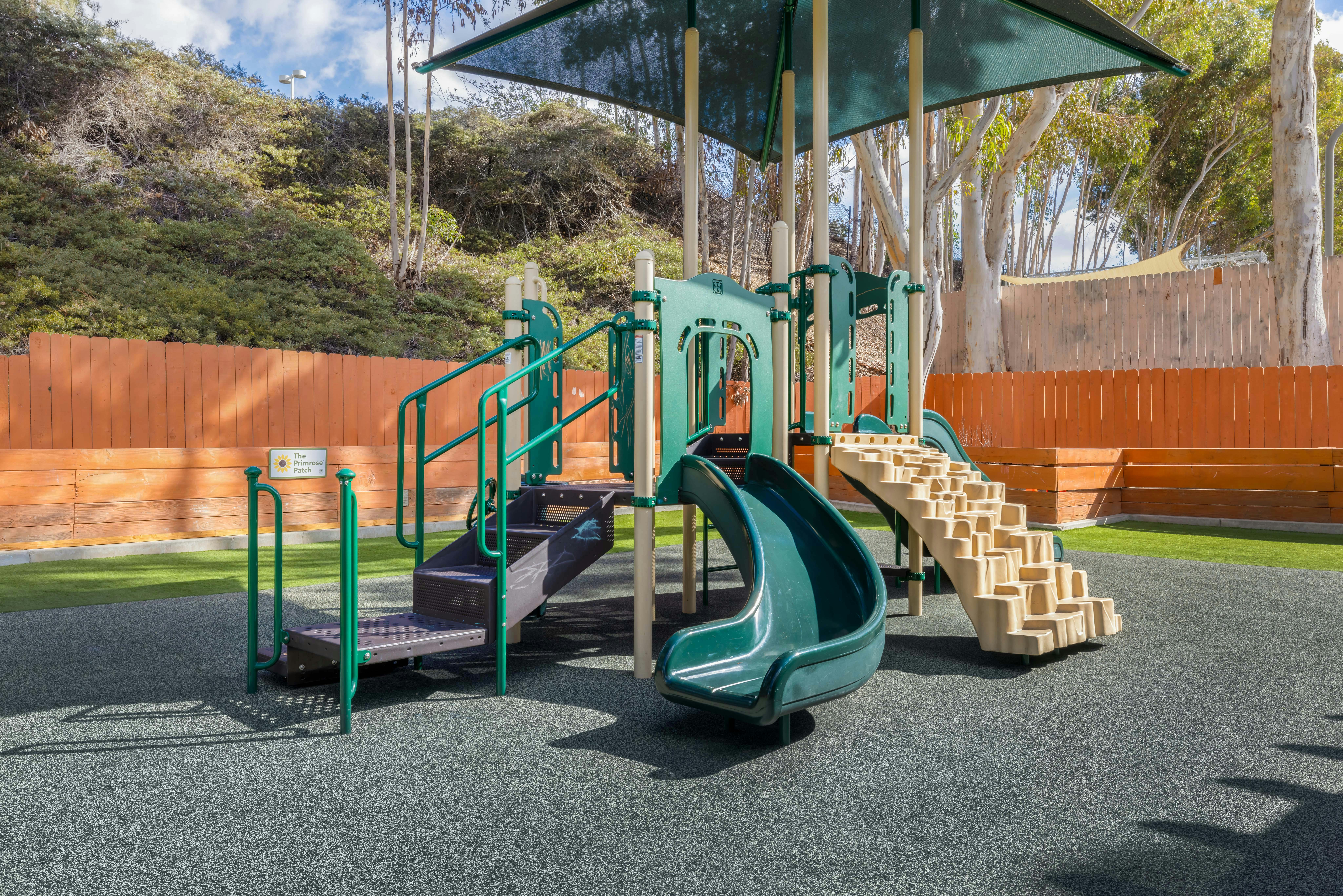 A green and tan playground set with slides and climbing structures