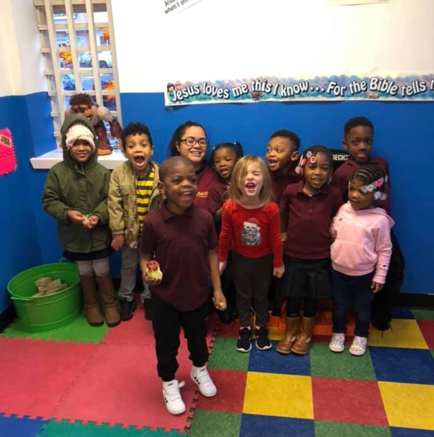 Group of children and an adult standing together in a room