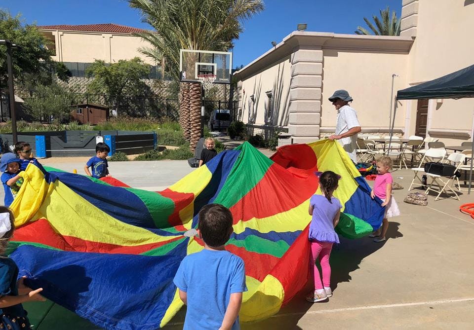 Children playing with a colorful parachute outdoors