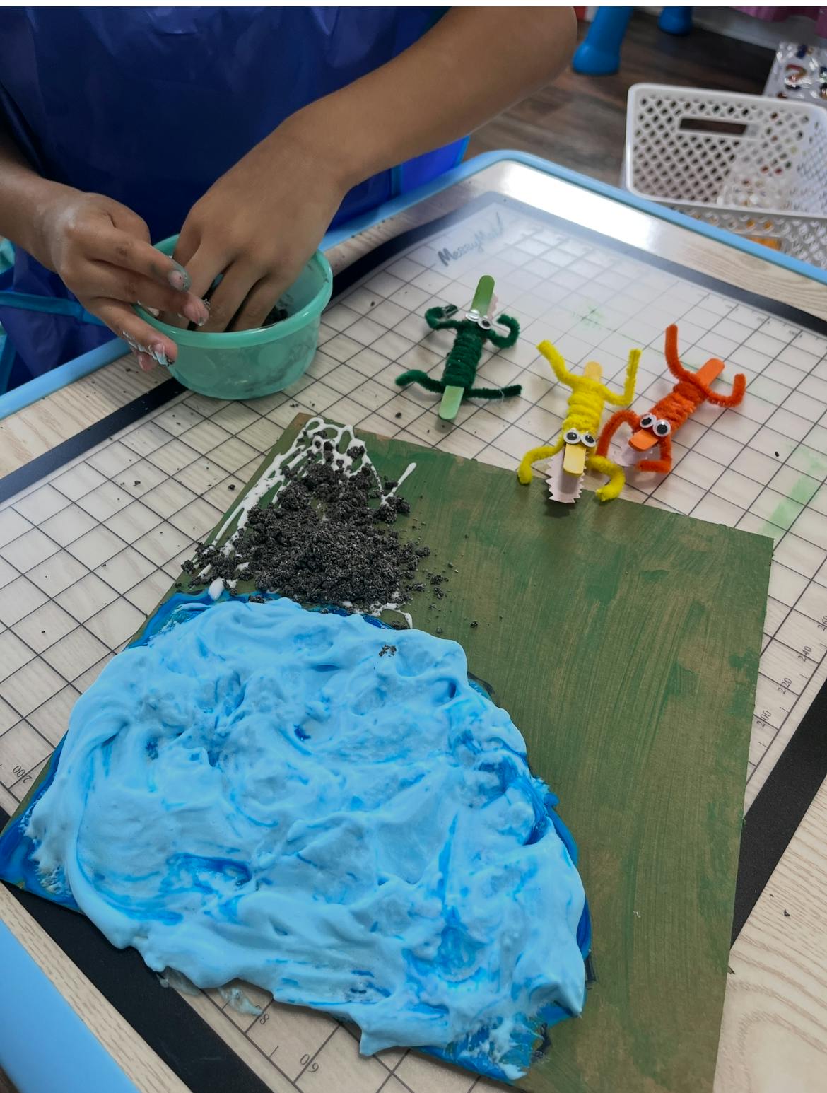 Child's hands mixing materials in a bowl next to a craft project