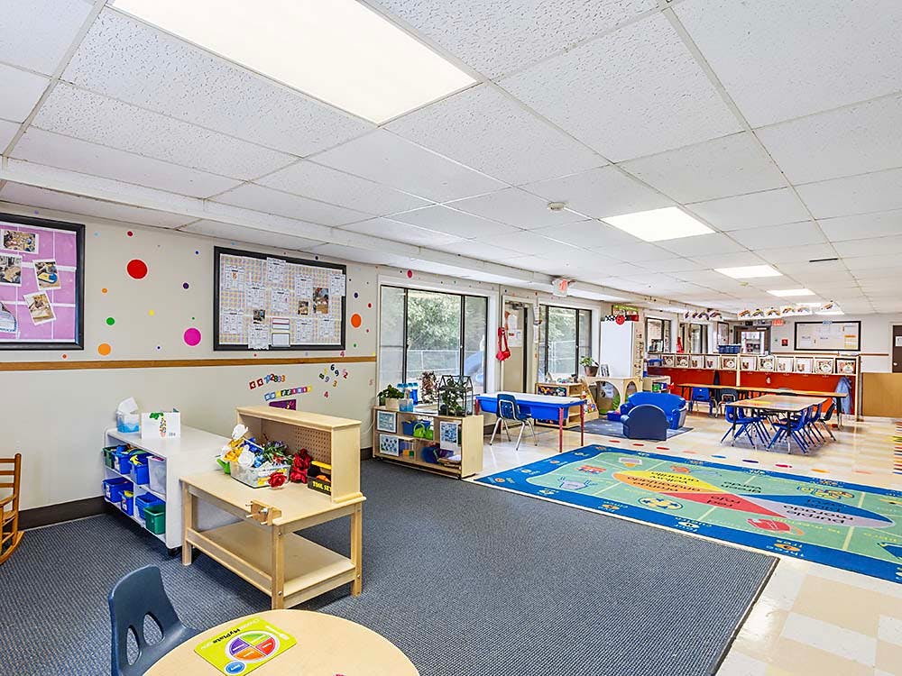 Classroom with child-sized tables, chairs, play areas, and colorful decorations