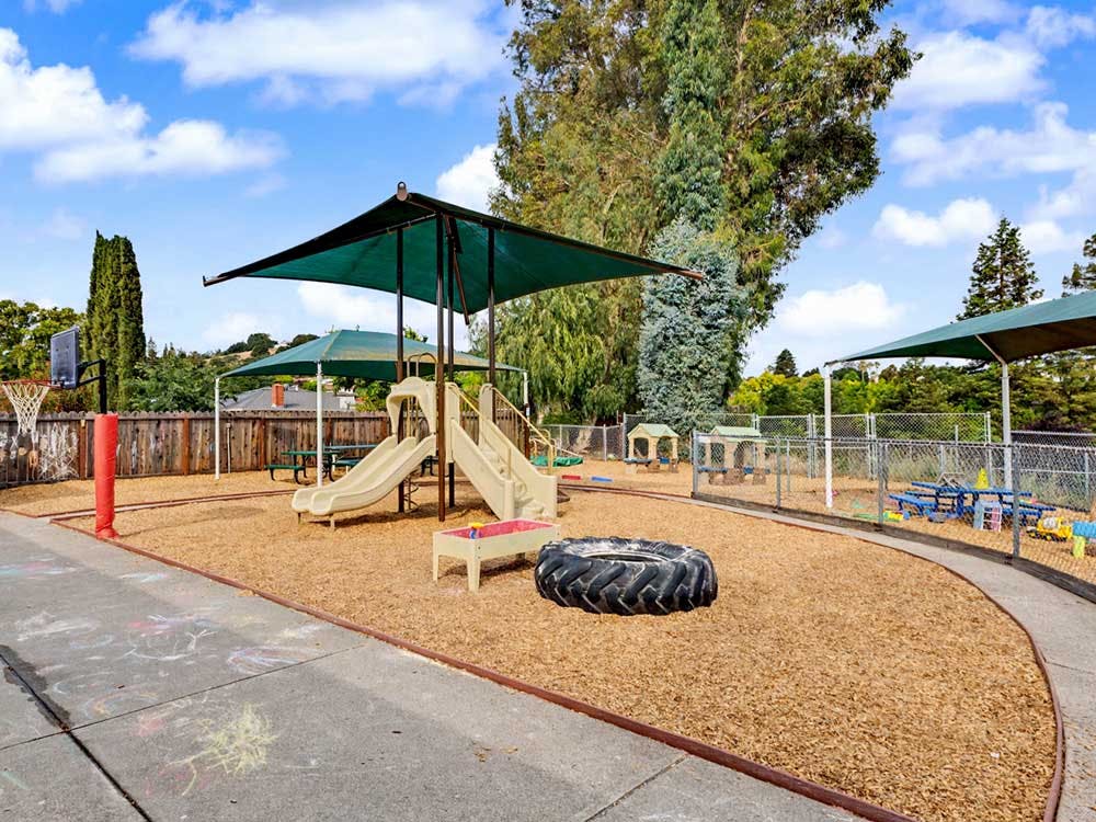 A outdoor playground with a slide and shade structures