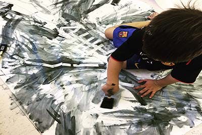 Child painting on a large sheet of paper with a brush