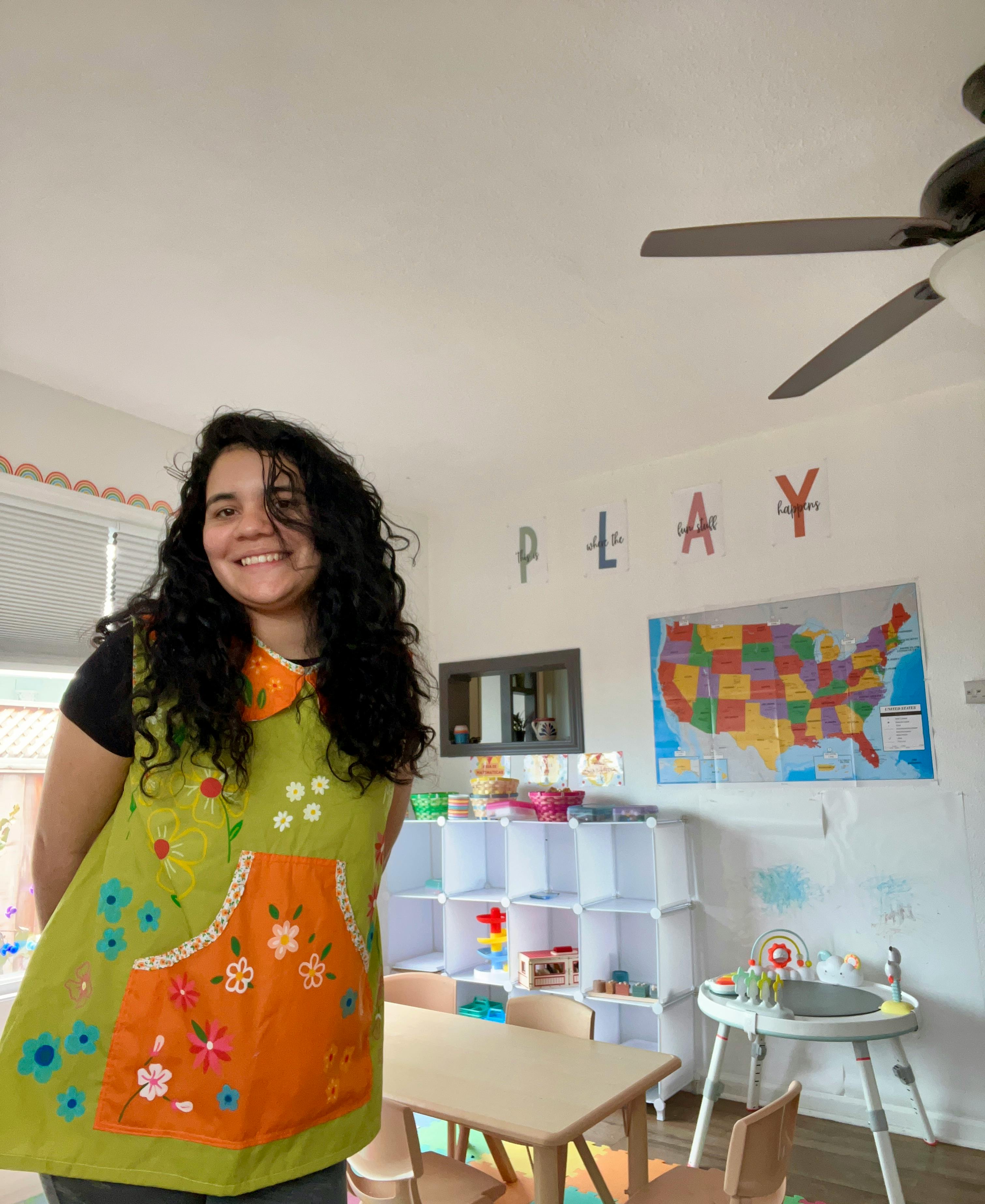 Smiling person in a floral apron in a classroom