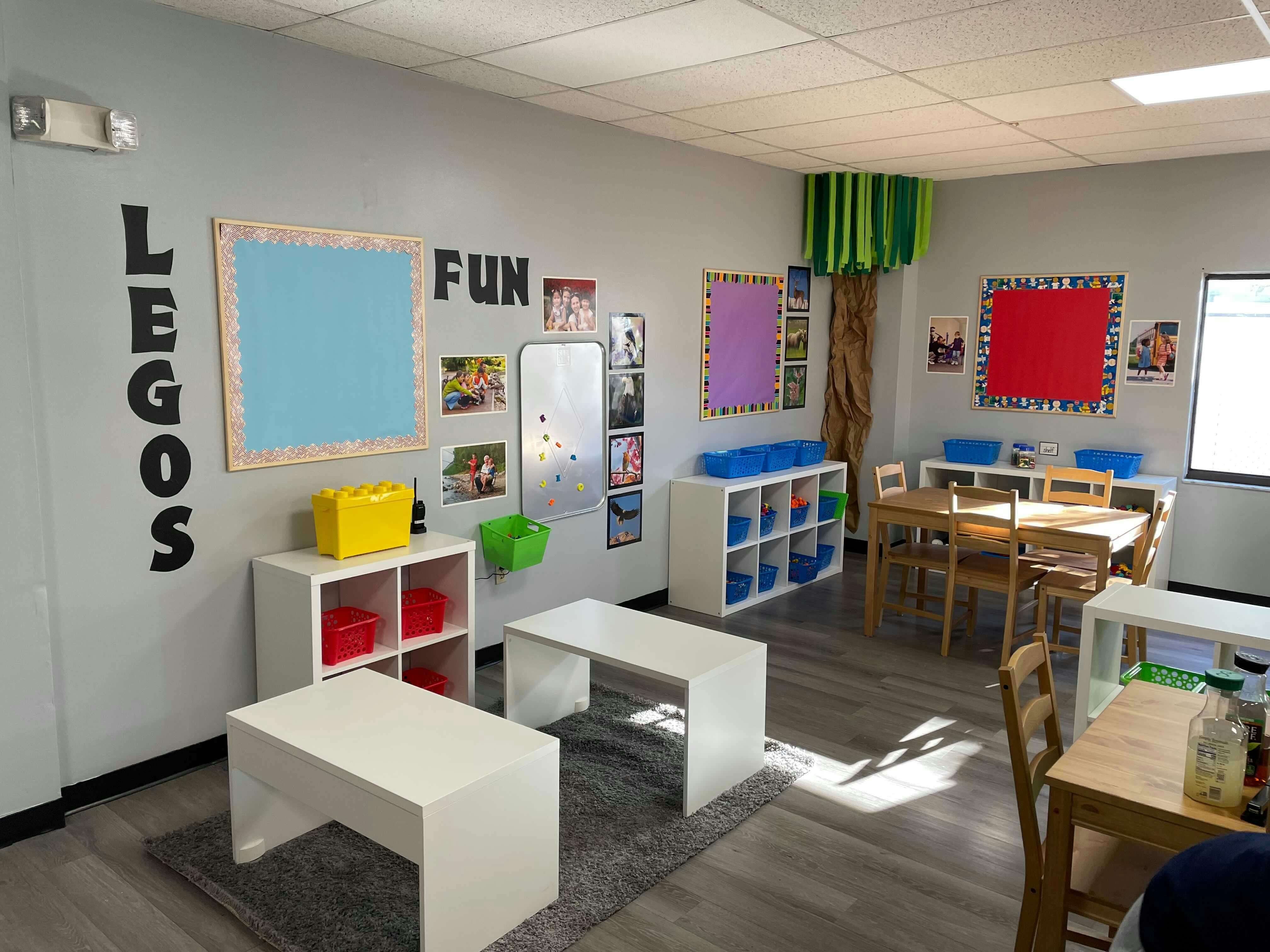 Playroom with tables, chairs, storage shelves, and wall decorations