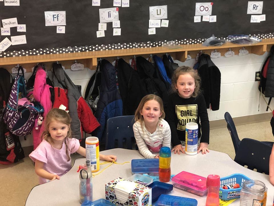 Three children at a table in a classroom