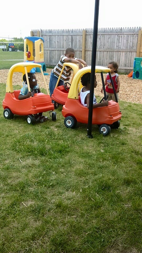 Children playing with toy cars on a grassy area
