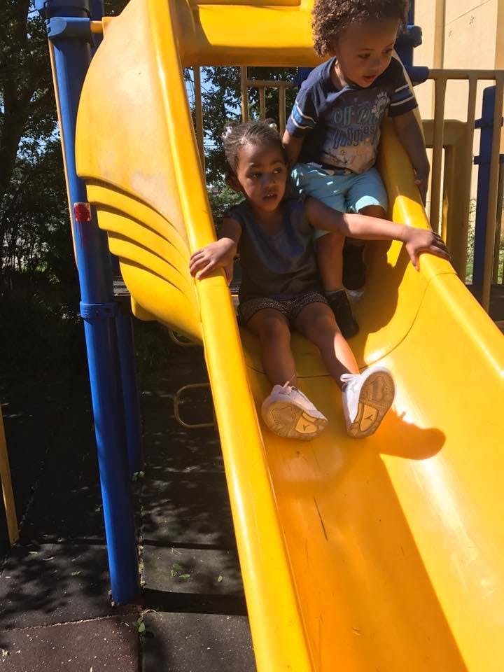 Two children on a yellow playground slide