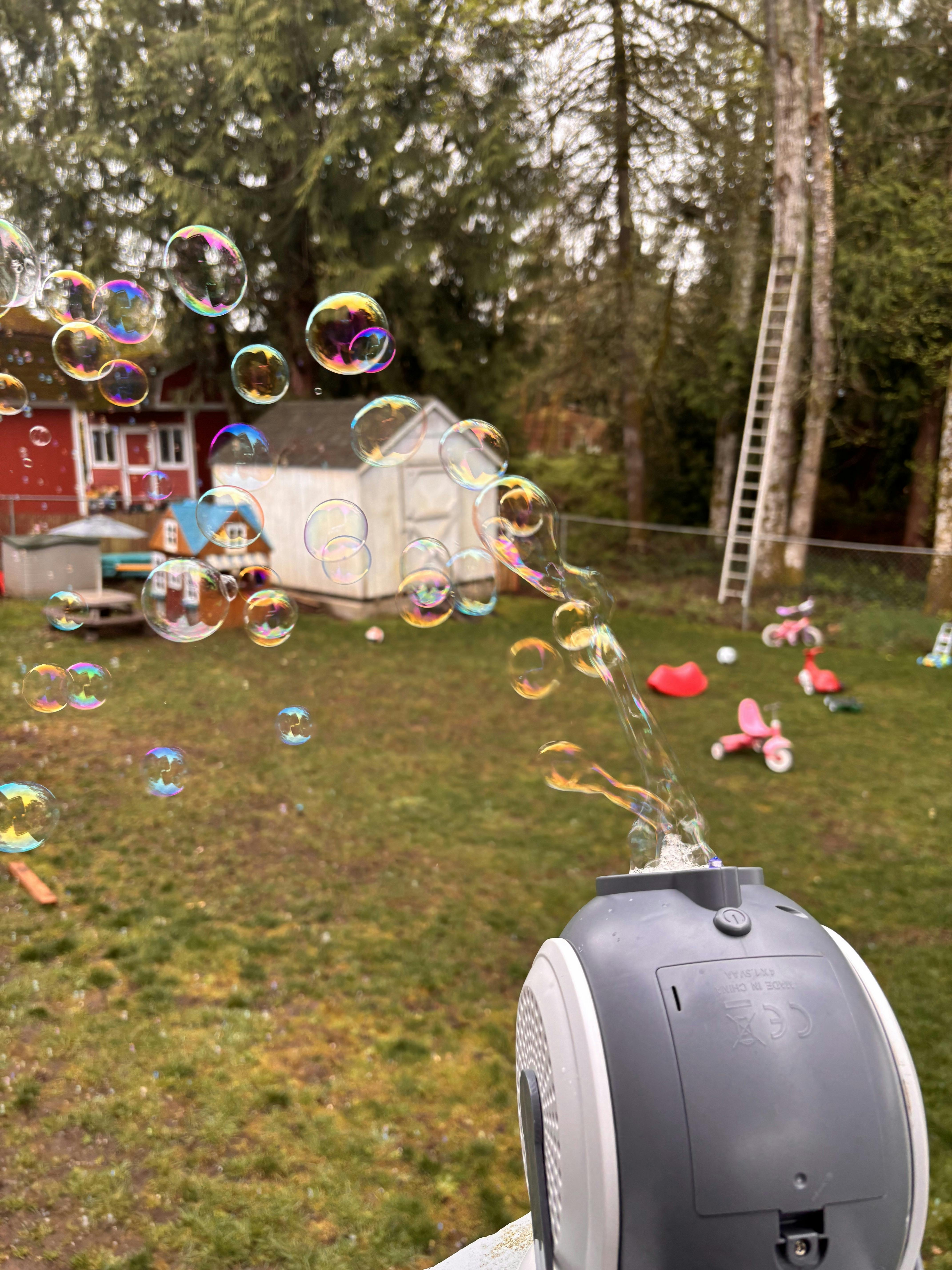 Bubble machine blowing bubbles into a backyard