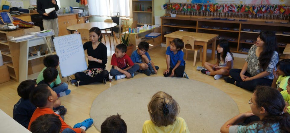 Adult holding a white board for children sitting in a circle in a classroom