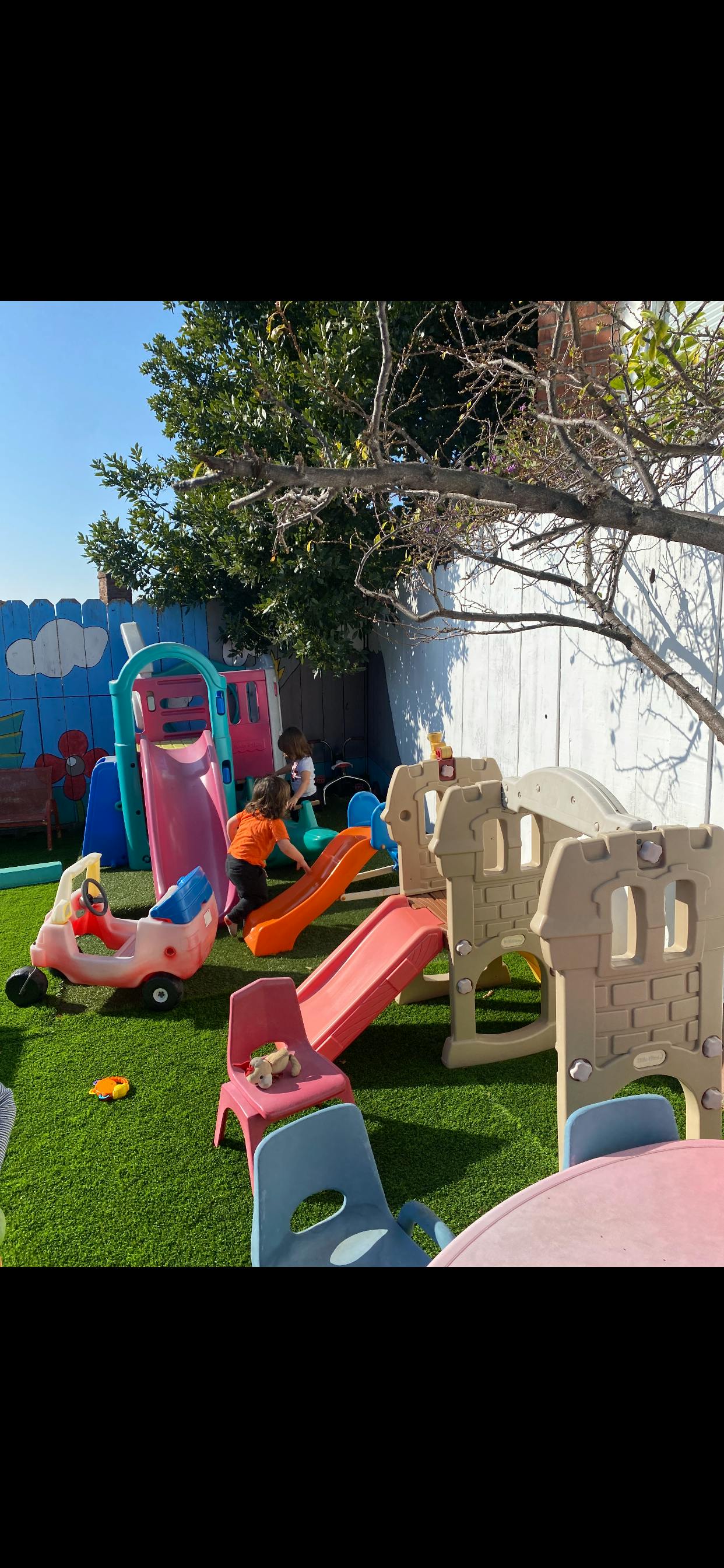Children playing on slides and play structures in a backyard