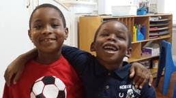 Two children smiling with arms around each other