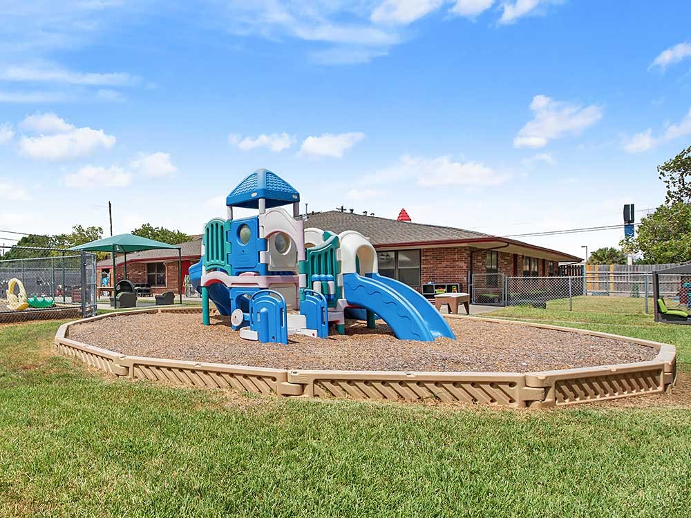 A colorful playground with slides and climbing structures on wood chips