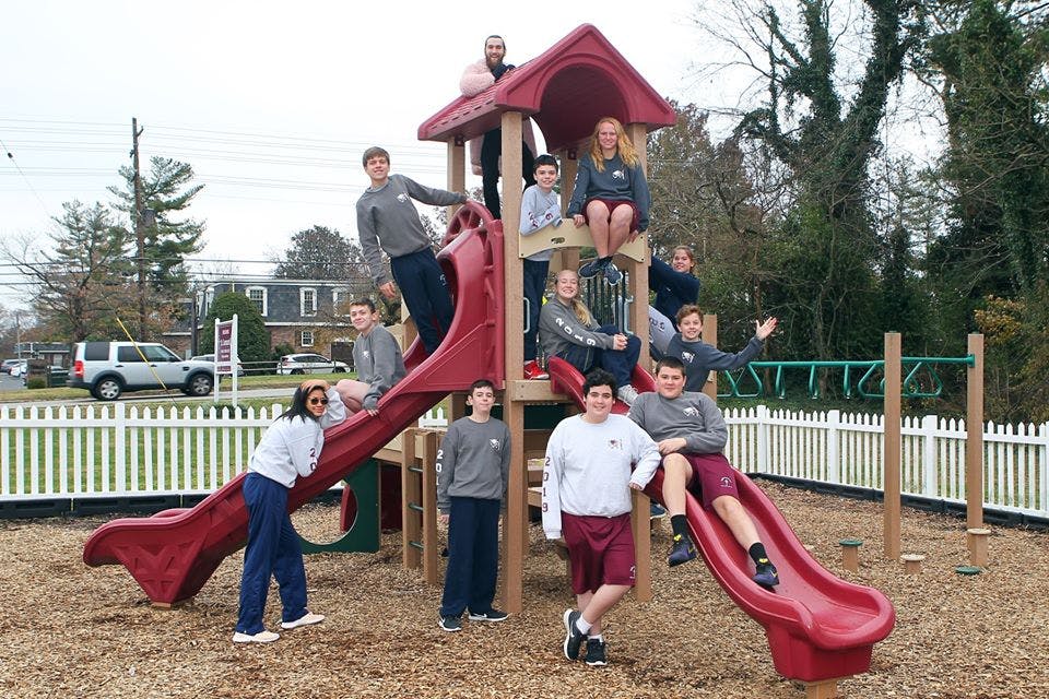 Group of teens on a playground structure with slides