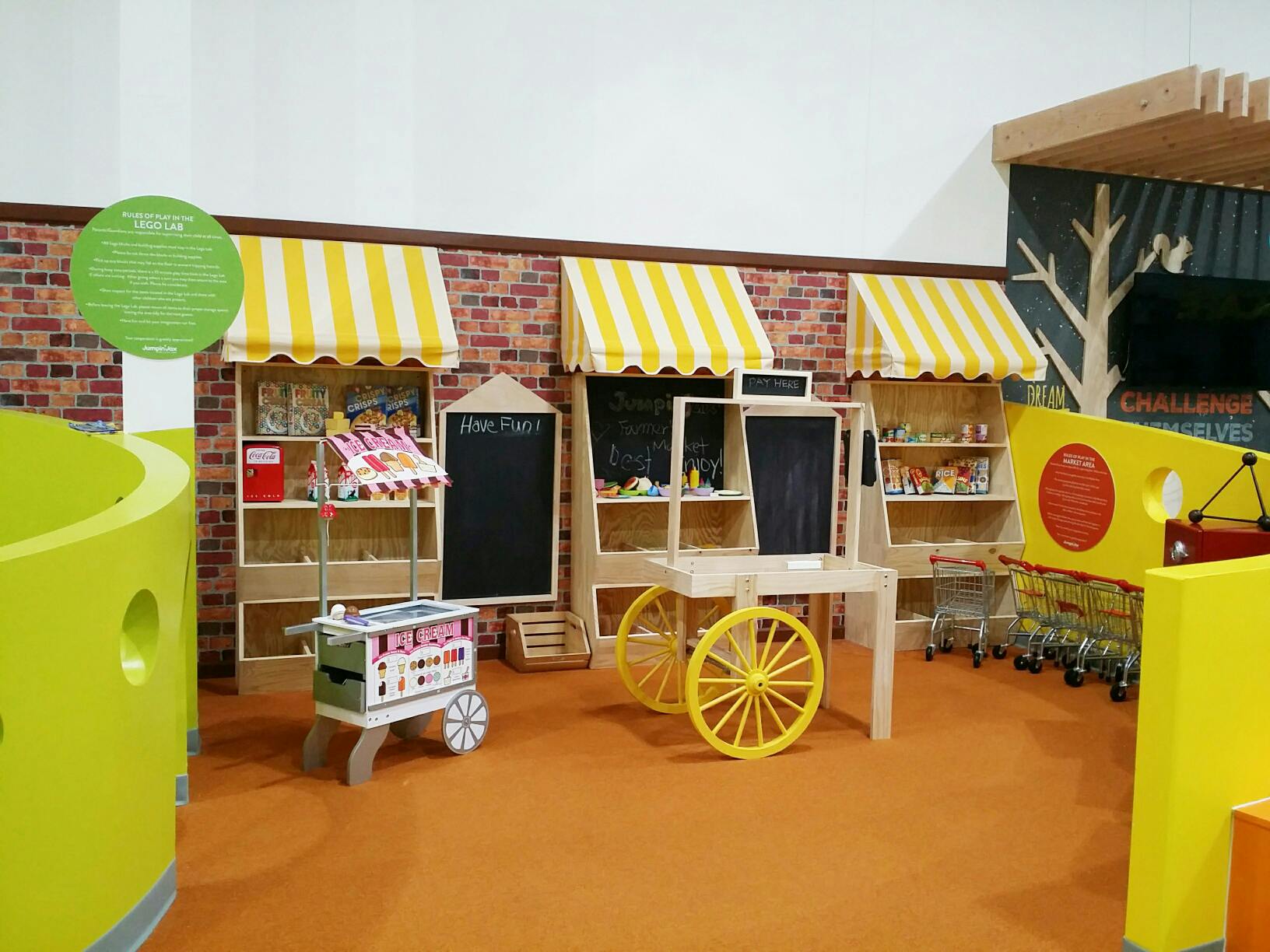 Play market stalls with yellow and white striped awnings and a cart