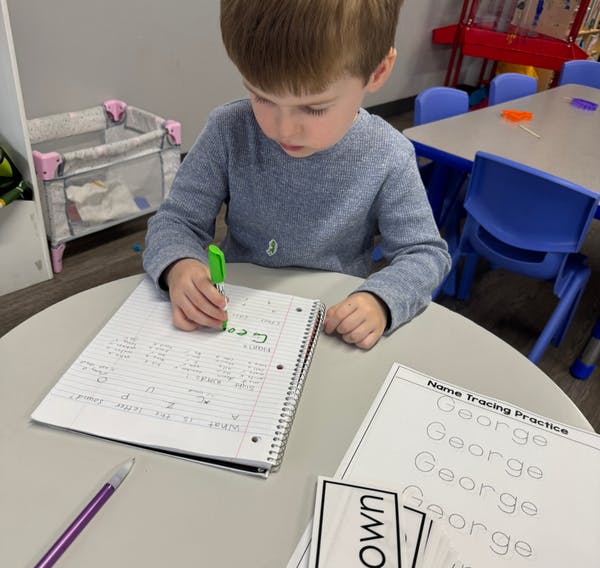 Child writing in a notebook at a table