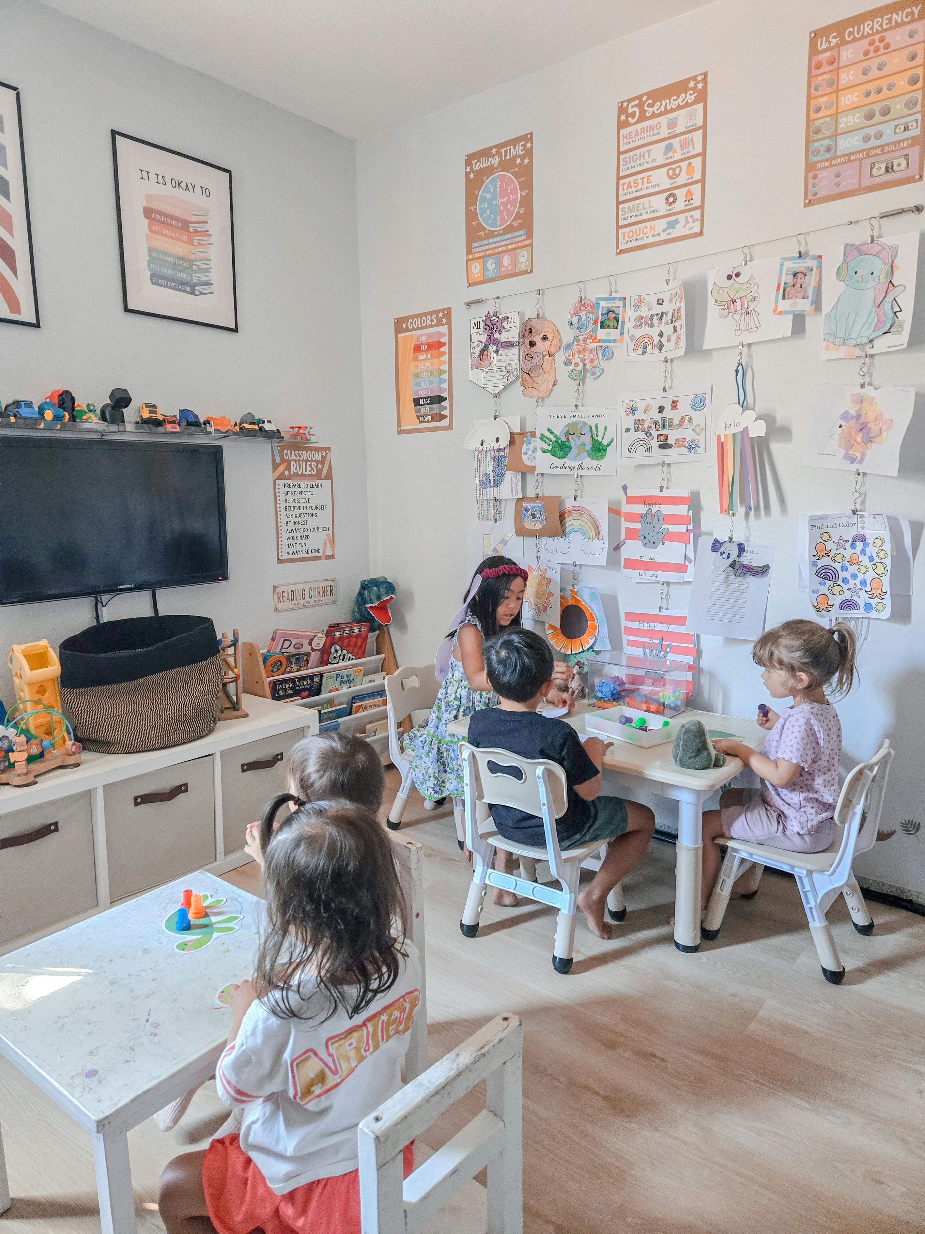Children sitting at tables in a playroom doing activities