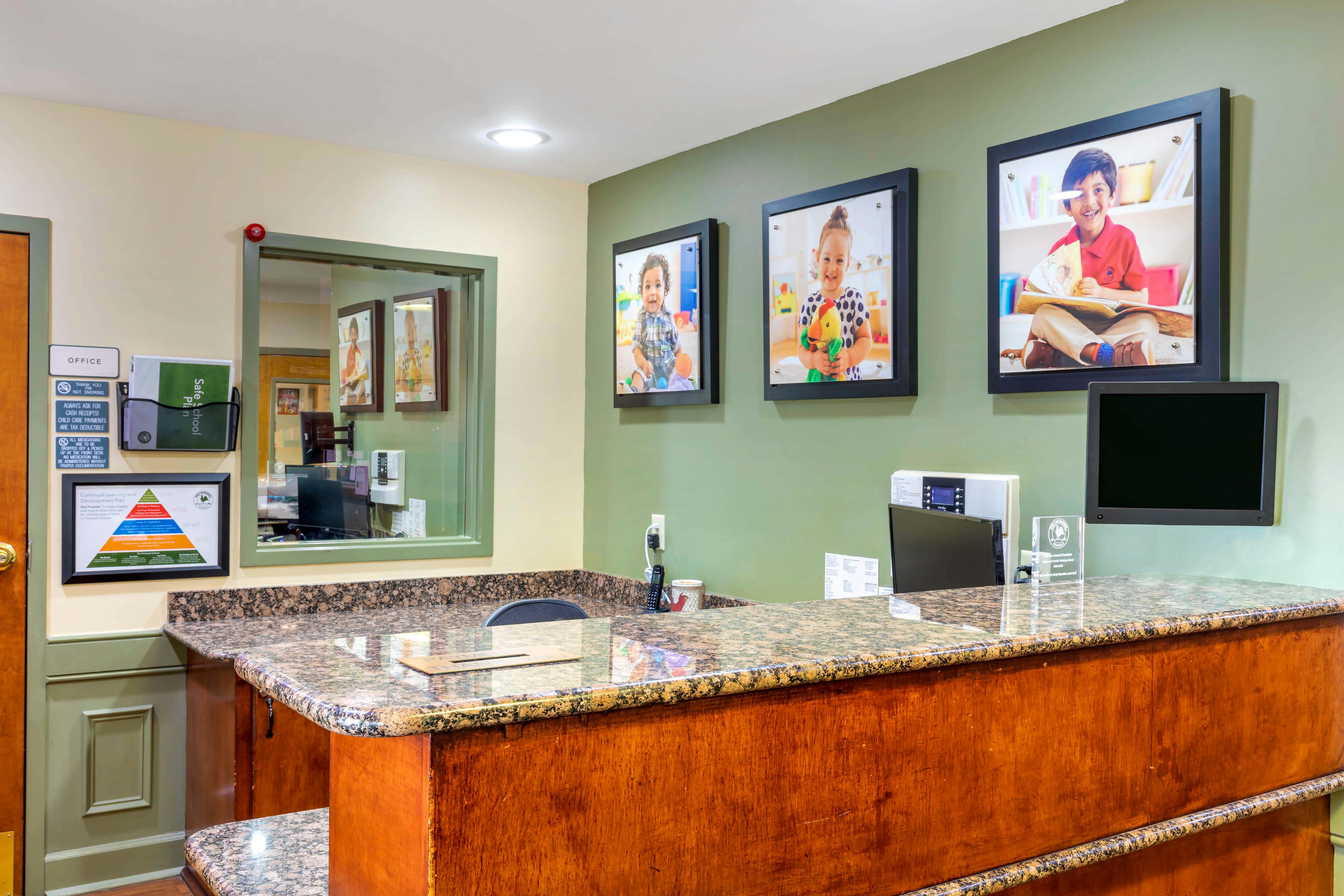 Reception area with a wooden counter, marble top, and framed pictures on the wall