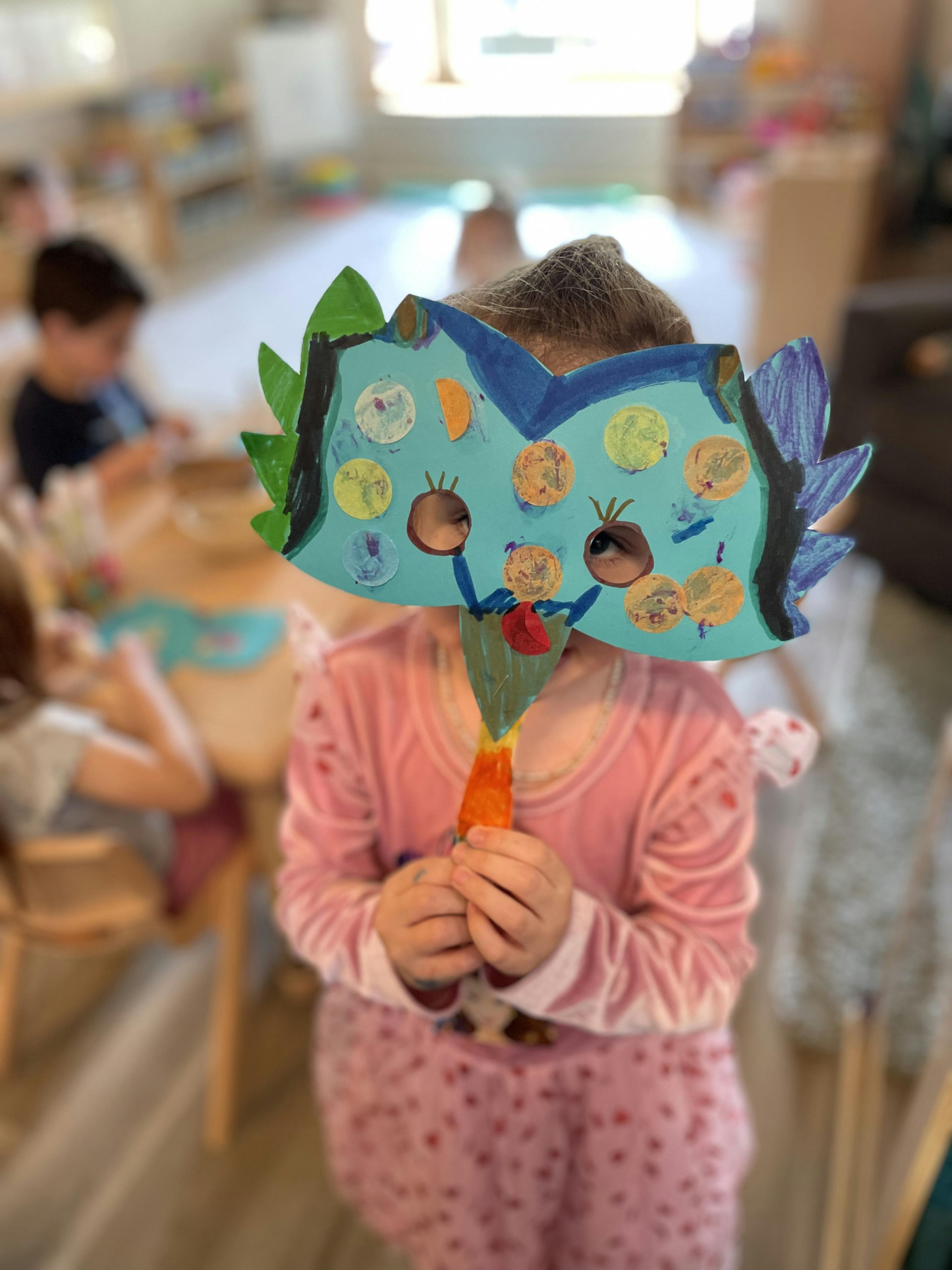 Child wearing a handmade blue mask with colorful circles, textured details