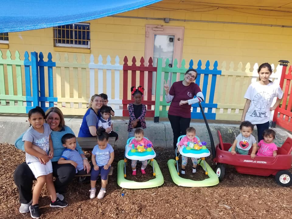 Adults and children posing outdoors with baby walkers and a wagon